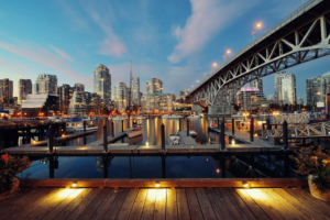 View of large city and metal bridge from boat docks in the evening.