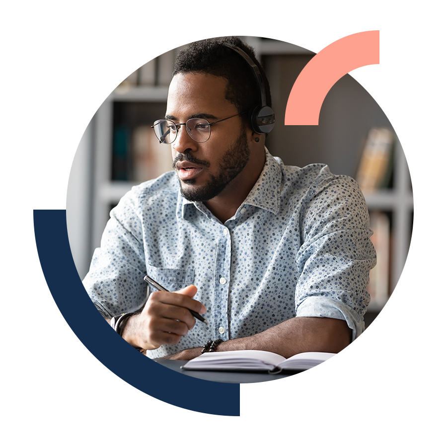 Focused young man wearing headphones watching webinar on laptop at desk.