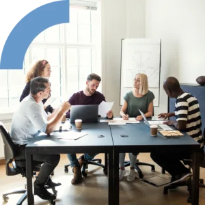 Group of professionals working together while sitting around a boardroom table in an office.