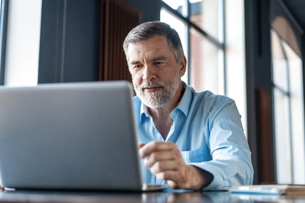 Man looking at a laptop that's open to a permitting application on the Citywide Customer Portal