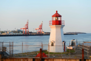Red and white light house along water in City of Saint John's.