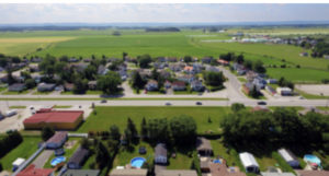 Drone view of small town surrounded by green fields.