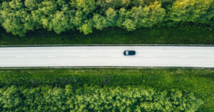 Aerial view of green summer forest with a road. Captured from above with a drone