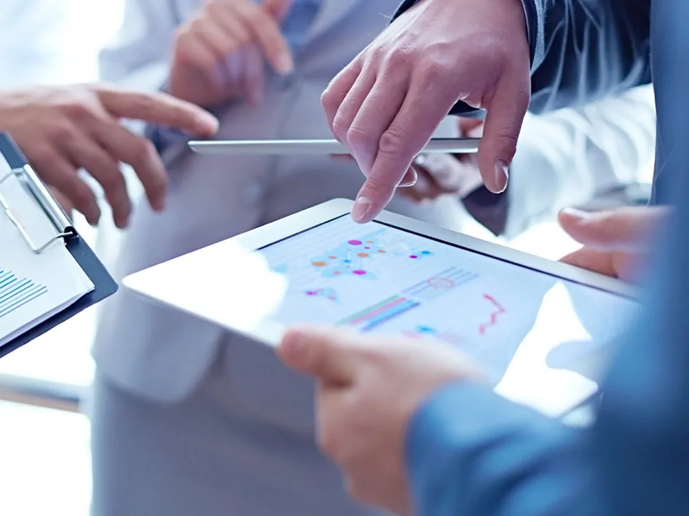 Group of coworkers hands pointing at data on a tablet.