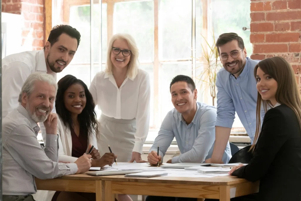 Group of smiling colleagues at a table in office space.