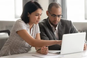 Colleagues in office working together on a laptop.