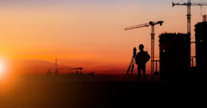 Silhouette of construction team working at site over blurred sunset background.