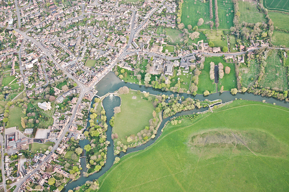 Aerial view of small town with river and meadow.