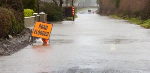 Flooded road with orange road closure sign.