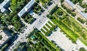 Aerial city view with crossroads, roads, houses, buildings, parks and parking lots.