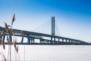 Metal and concrete bridge over frozen lake in Winter.