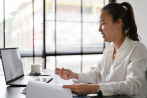 Young women working on a laptop as a desk in a bright office space.