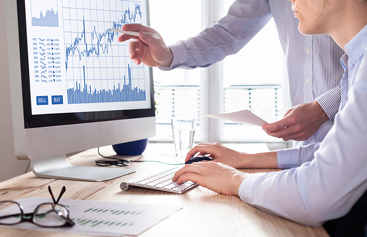 Two colleagues reviewing graphs on a desktop computer.