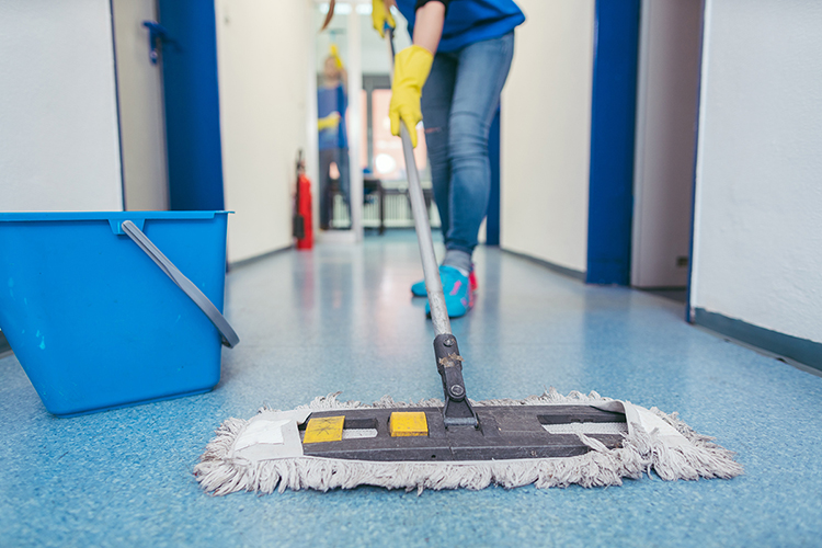 Close-up of cleaners moping the floor of a hall.