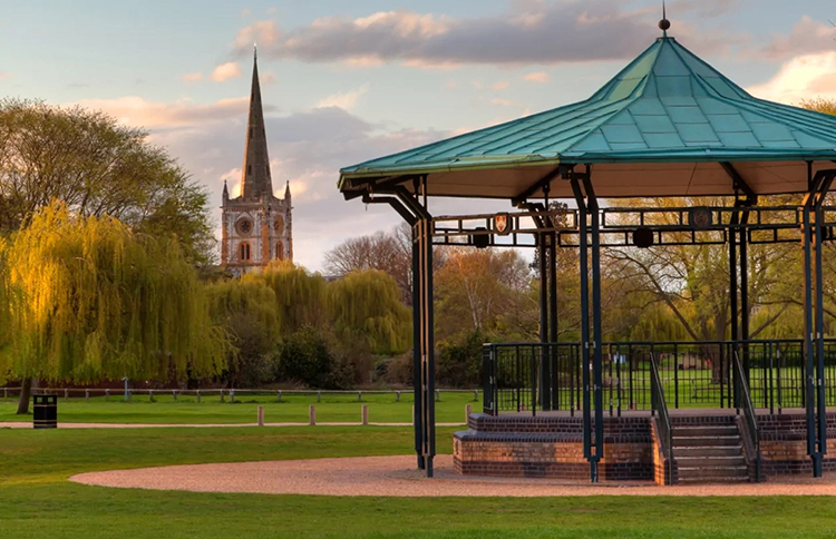 Outdoor gazebo with green, metal roof with open park area in the background.