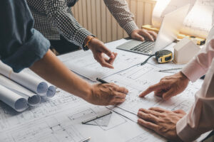 Hands of three people pointing to construction plans.