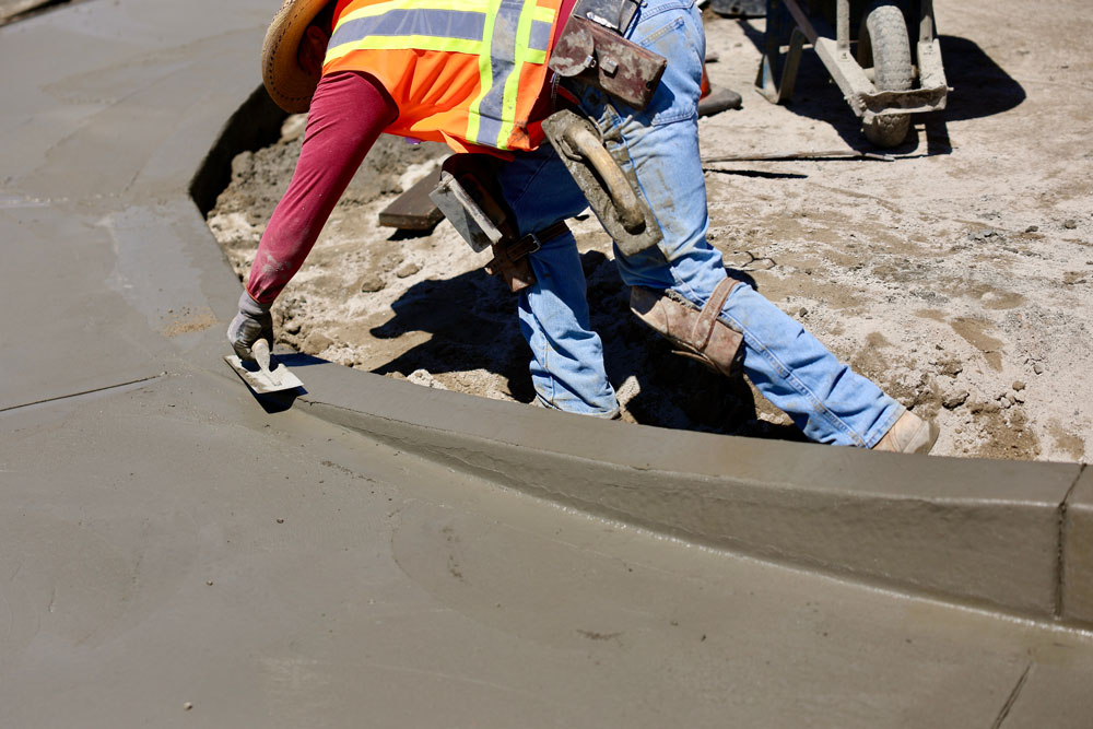 Concrete worker puts final touch on wet concrete.
