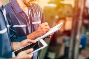 Facility manager and maintenance worker reviewing task workflows and facility maintenance operating guidelines within a CMMS on a tablet.