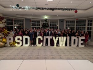PSD Citywide team group photo at holiday event with large illuminated “PSD CITYWIDE” letters, showcasing company culture and a transparent candidate journey within the PSD Citywide hiring process