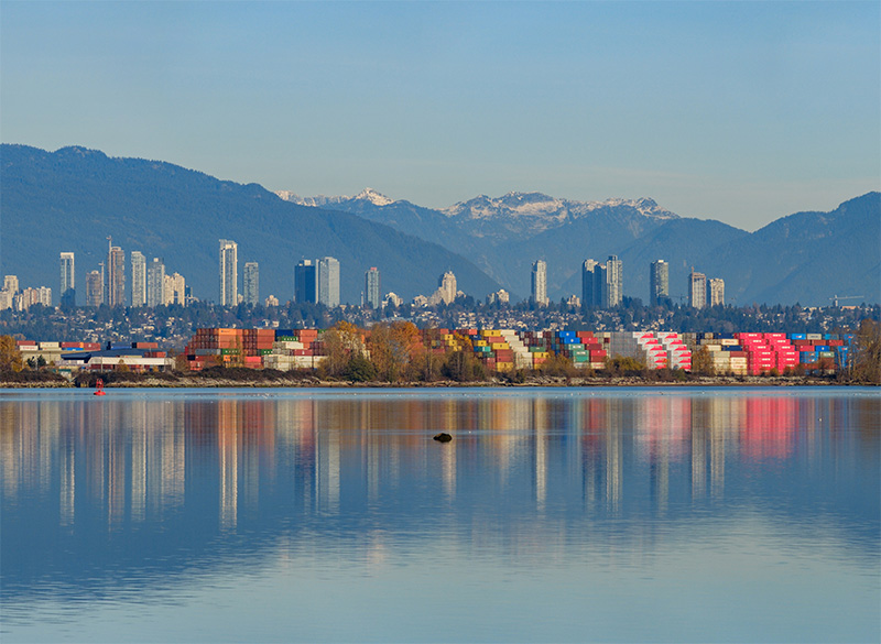 Panoramic view of river, city skyline, and mountains in Richmond, BC.