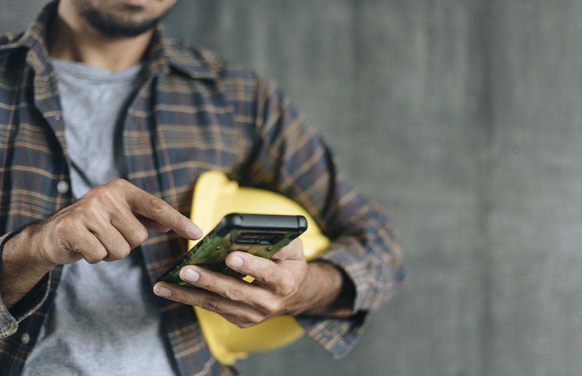 construction worker hands using smartphone on cement wall background with copy space